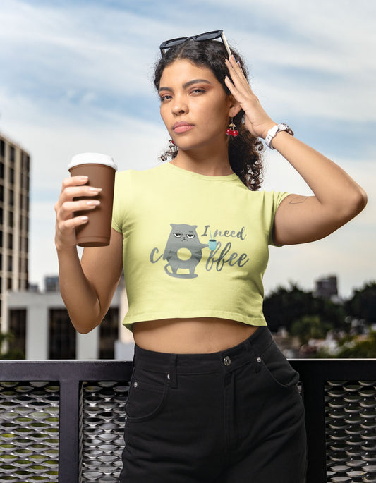 Unleash your cattitude and satisfy your caffeine cravings with the Womanitee Women's Coffee Cat Crop Top. This butter yellow crop top showcases a delightful illustration of a cat and the witty phrase 'I Need Coffee.' Embrace your love for cats and coffee in a fashionable and humorous way!