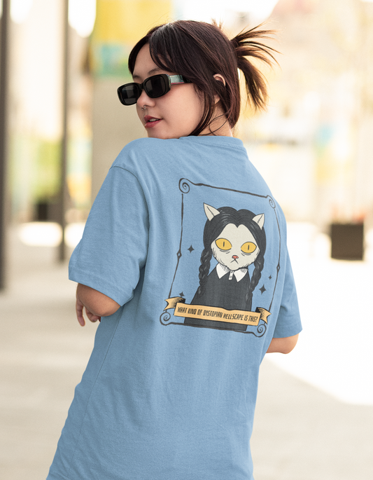 Embrace your dark humor with our sky blue oversized t-shirt featuring a cat-themed cartoon illustration resembling Wednesday Adams from the Addams Family and the iconic quote "What Kind of Dystopian Hellscape is This?" Shop now at Womanitee, the best place to buy women's graphic tees online in India